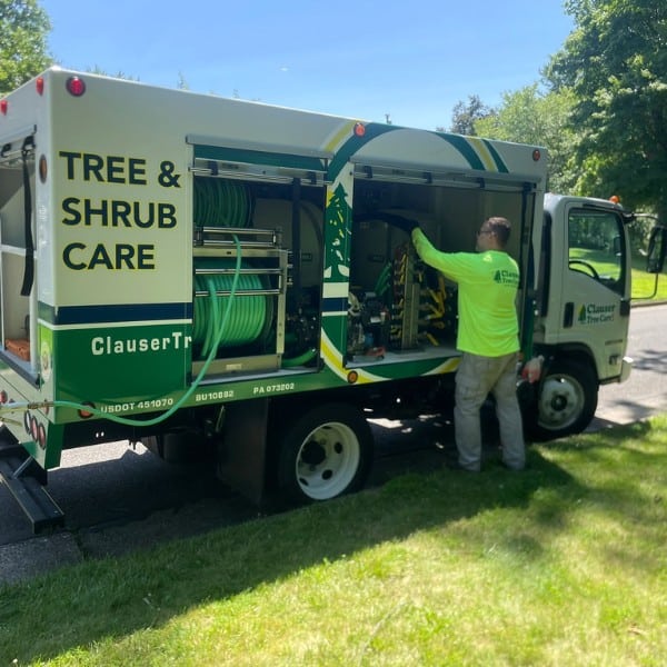 Clauser Tree Care technician loading equipment into branded PHC service truck